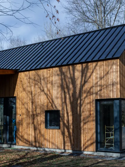 A wooden house with a black roof and windows