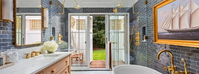Dark blue subway tiles, gold accents, sailboat art, and garden views – McPhee Associates of Cape Cod.