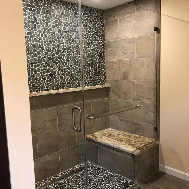 A bathroom with a walk in shower with a glass door