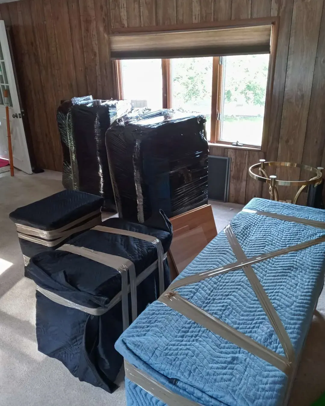 A living room filled with furniture wrapped in plastic and tape.