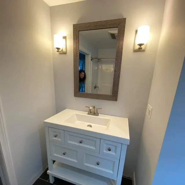 New bathroom vanity with sconce lighting and framed mirror