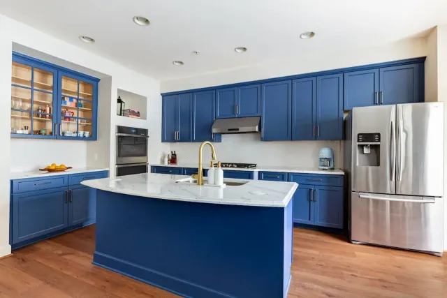 Updated kitchen with white countertops, blue cabinets, and blue island