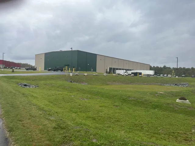 A large building with a green roof in the middle of an open field.
