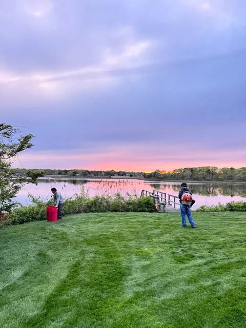 GB Landscape crew maintaining a waterfront lawn at sunset