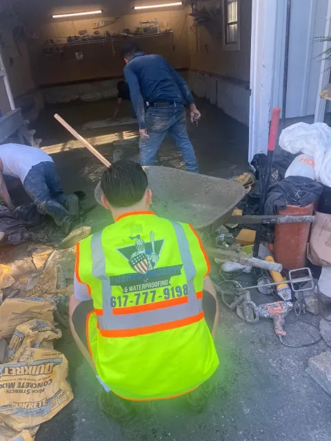 Construction workers are pouring concrete in a garage.