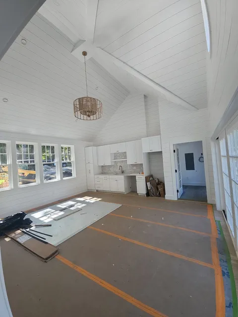 White painted shiplap vaulted ceiling with exposed beam, pendant light fixture, and white cabinetry in residential interior