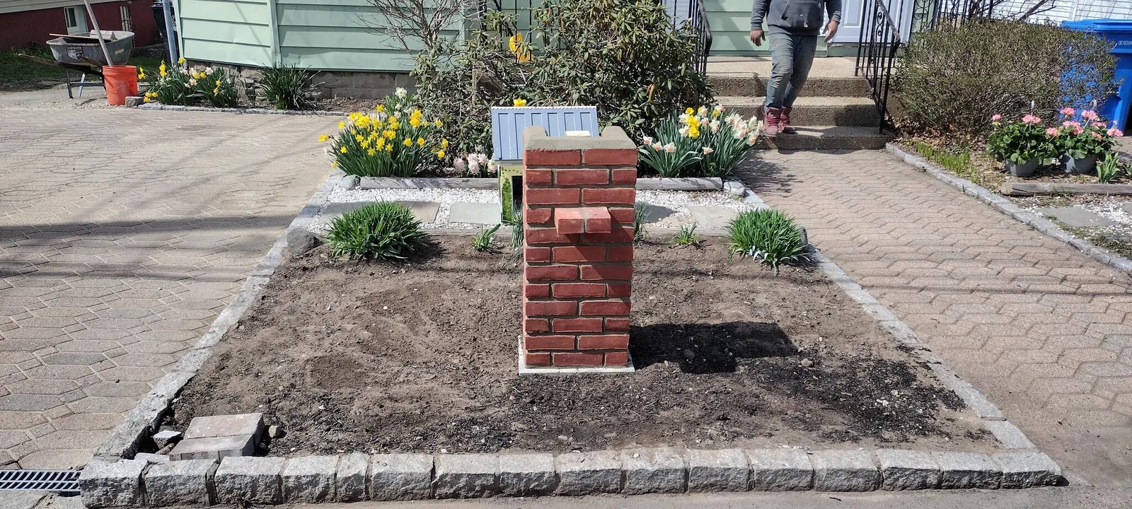 Brick pillar and granite cobble edging in a front walkway bed