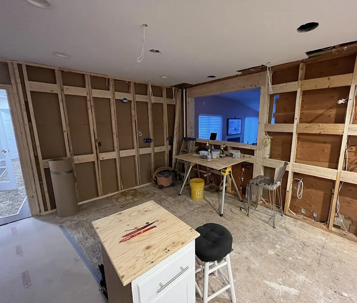 a remodel in process with holes cut out in the ceiling and recessed lights being installed and new wiring run throughout the remodel