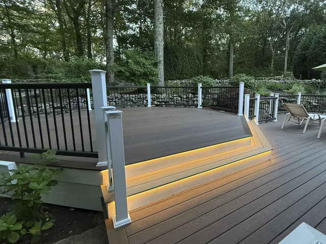 Multi-level composite deck featuring under-stair LED strip lighting and black metal balusters.