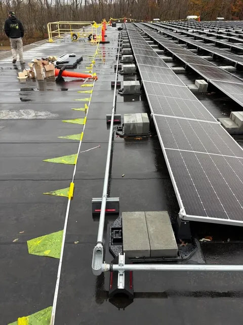 Solar racking and conduit installation on a wet commercial roof with safety flagging