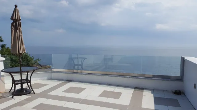 A table and umbrella on a balcony overlooking the ocean.