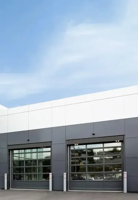 G-4400 commercial glass garage doors (12×12) with Iron Ore frames, installed on a modern commercial building in Lincoln, RI by Quality Overhead Doors