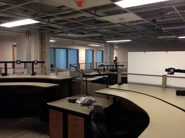 Modern office interior with workstations, chairs, windows, and exposed ceiling pipes