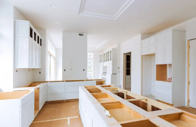 A kitchen under construction with white cabinets and wooden counter tops.