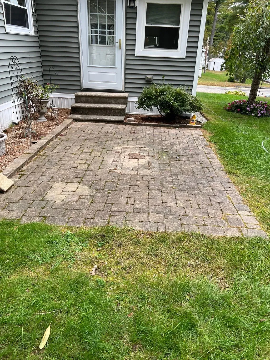 There is a brick patio in front of a house.