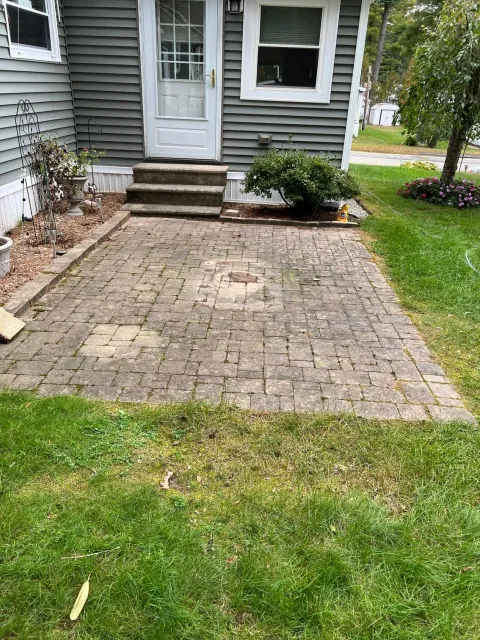 There is a brick patio in front of a house.