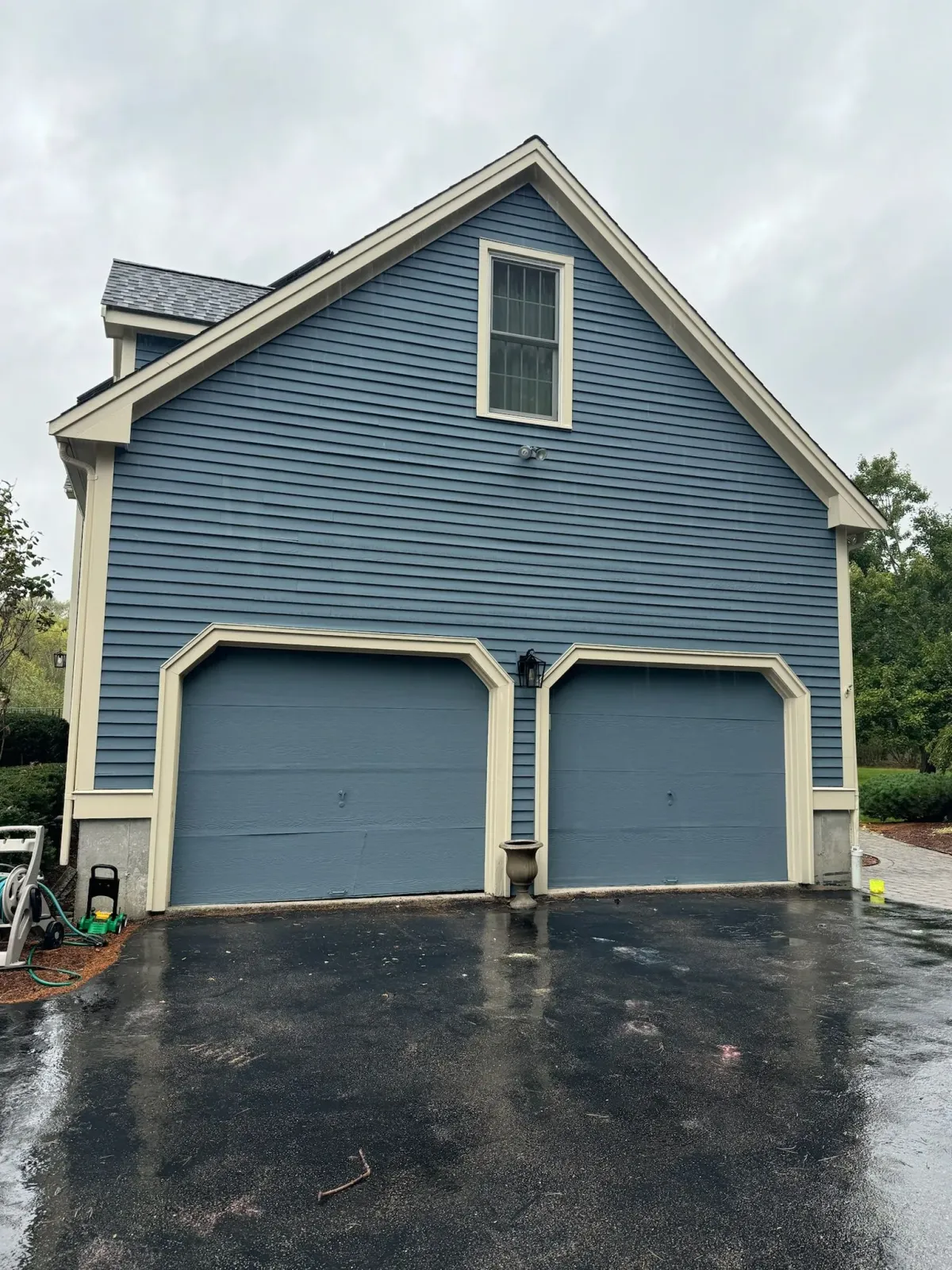 A blue garage with two garage doors and a window