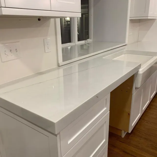 A kitchen with white cabinets and a white counter top.