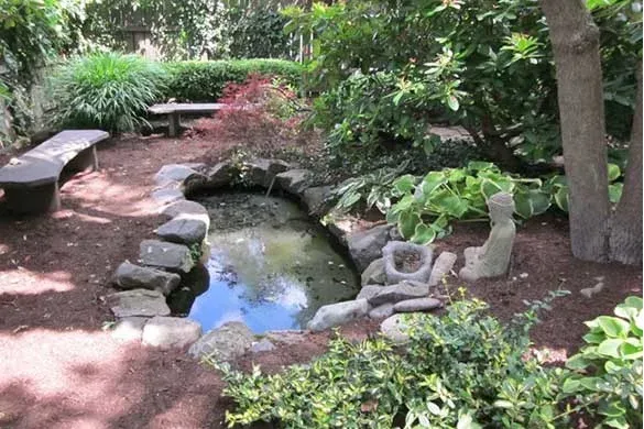 Naturalistic garden pond with stone edging and benches