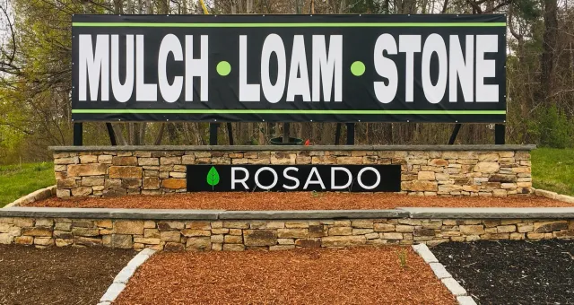 Sign for landscaping materials reading "Mulch Loam Stone" with the name "Rosado" below.
