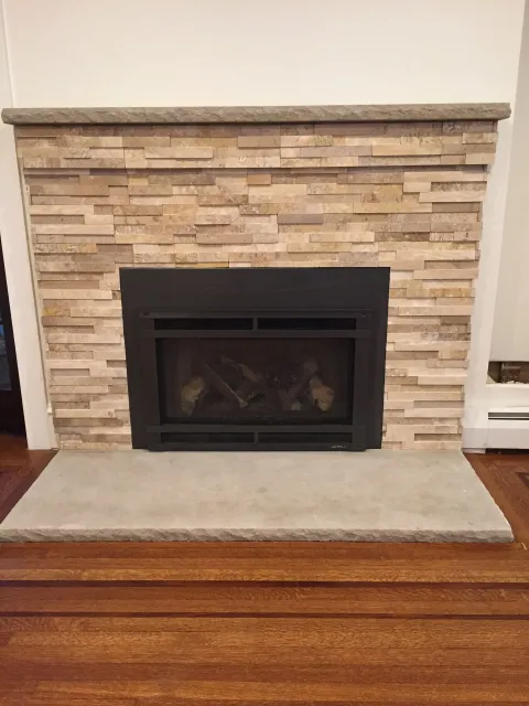 A fireplace with a stone wall and a wooden mantle