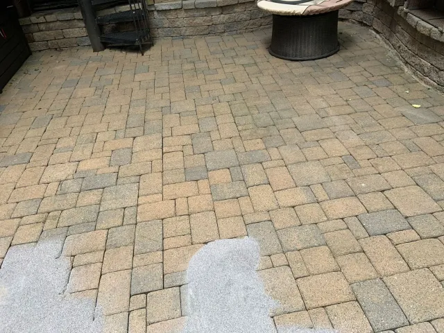 Brick patio with a small round table and wet patches near the foreground.