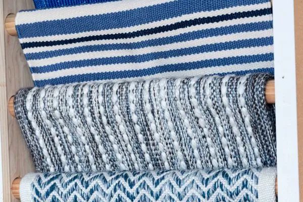 Close-up of rolled carpets in blue, white, and gray patterns. Perfect for home carpet and floor installation projects, these textures add warmth and style.