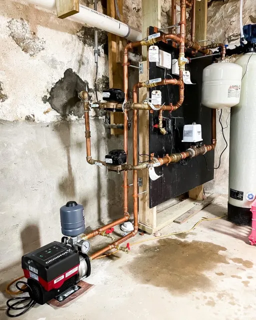 A room with a lot of pipes and a water heater.