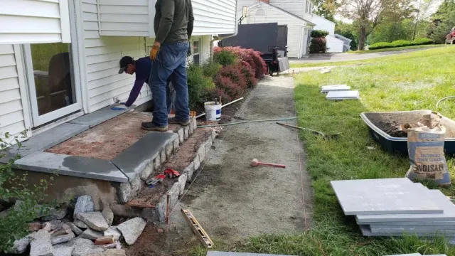 Two men are working on a porch of a house.