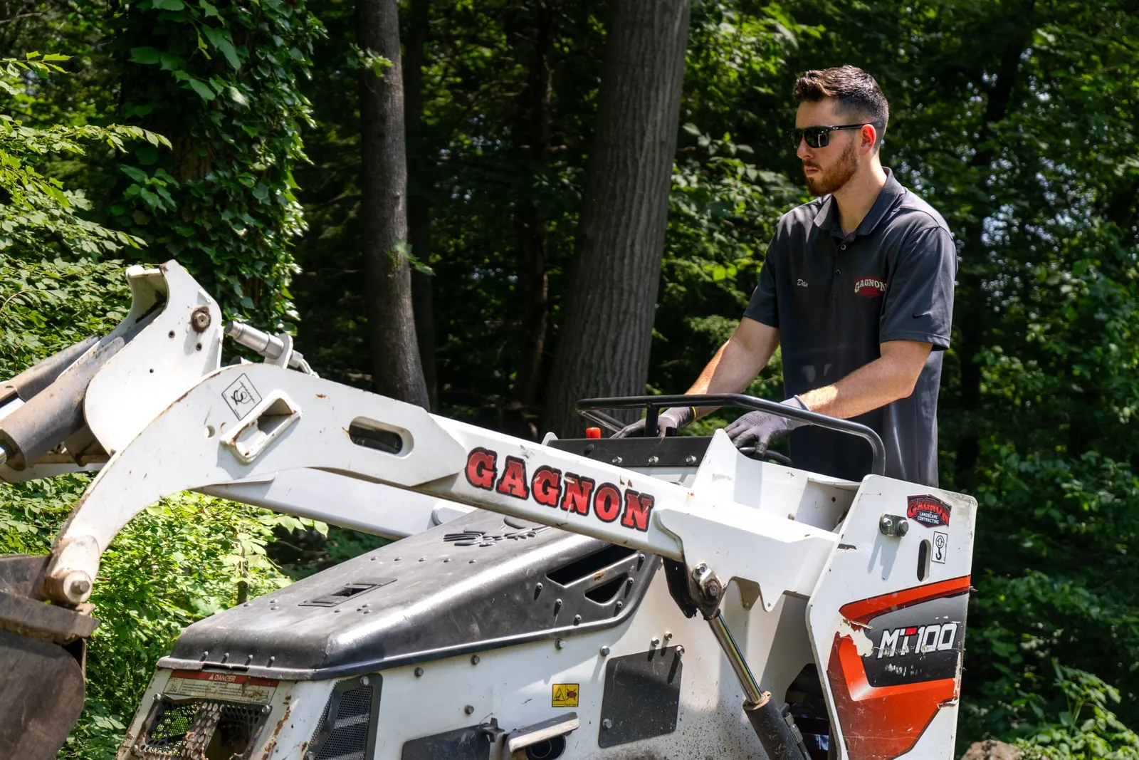 Man operating skid steer in wooded area