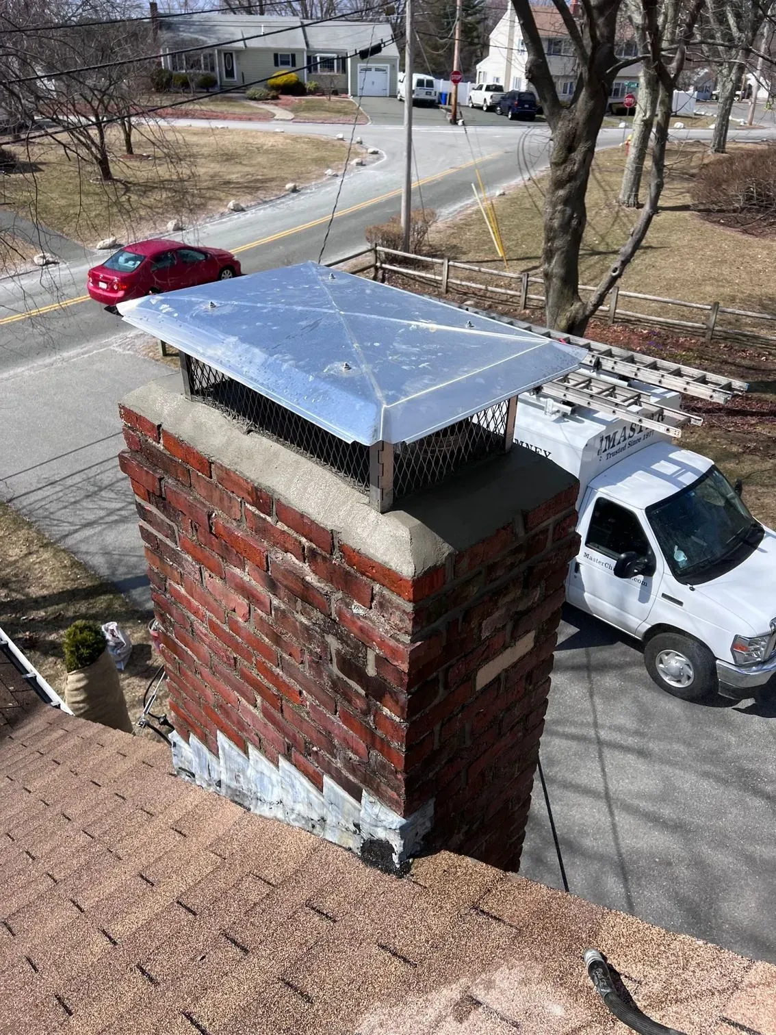 A white truck is parked next to a brick chimney.