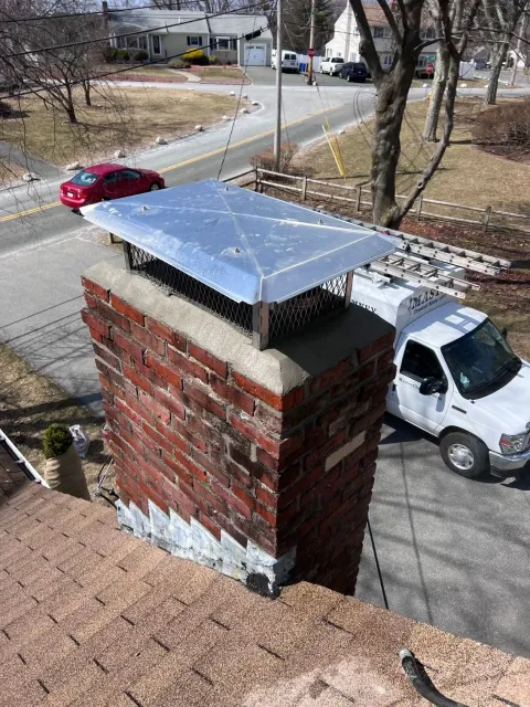 A white truck is parked next to a brick chimney.