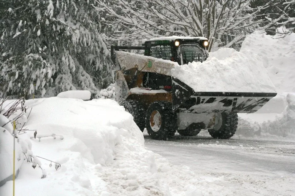 Snowplow clearing a snow-covered road in a winter landscape.