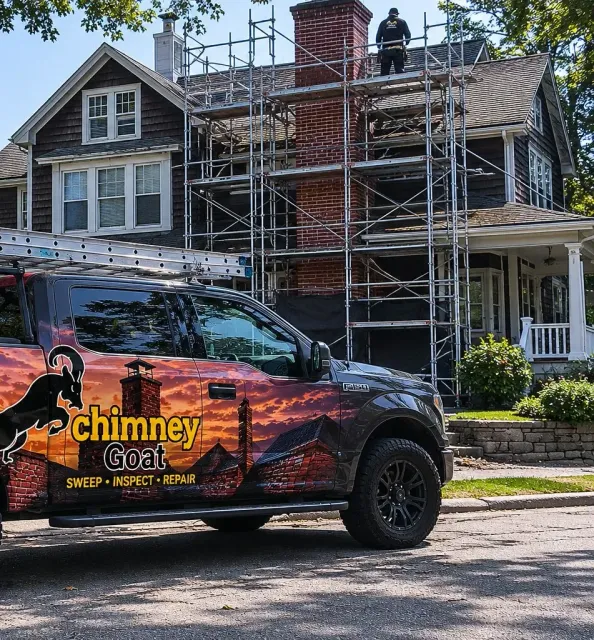 Chimney Goat truck at a Boston chimney rebuild job with rooftop scaffolding