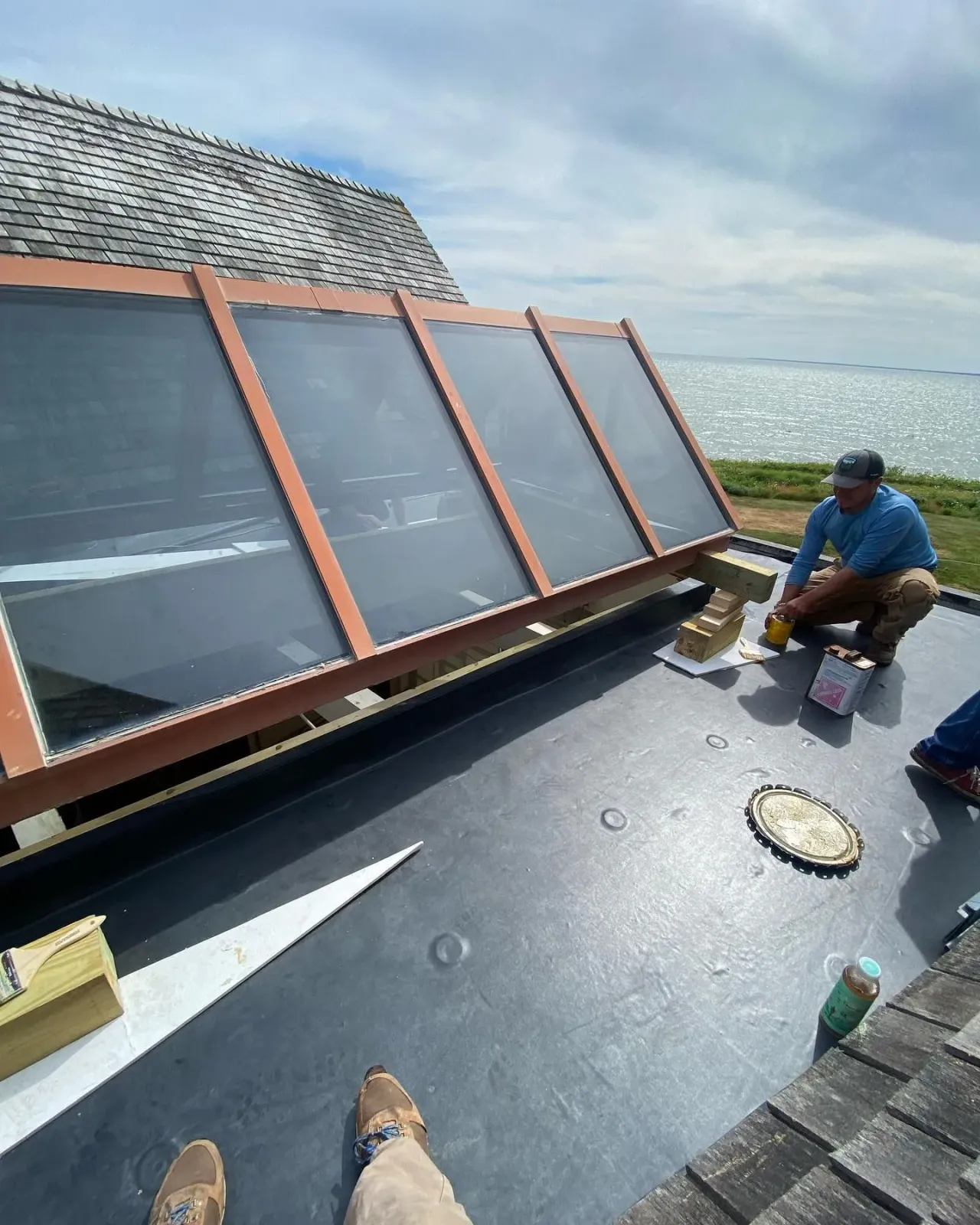 Worker installing solar panels on a rooftop beside the water.