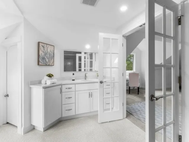 A bathroom with white cabinets and a french door