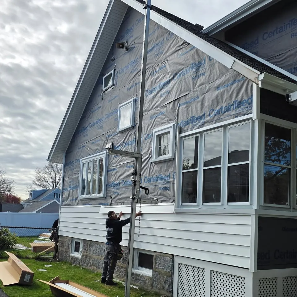 Housewrap going up on a gable end during a siding job