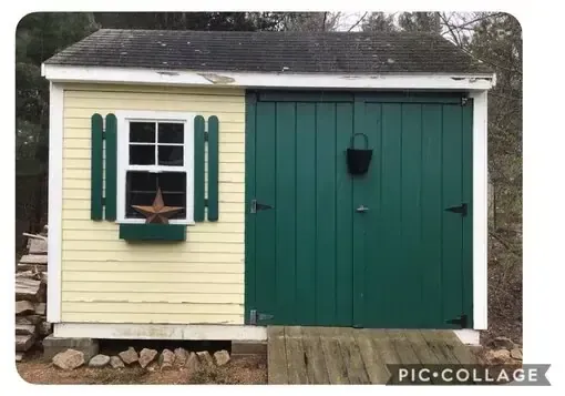 Small cream-and-green shed with shuttered window, double doors, and a hanging planter.