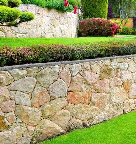 Professional hardscaping service with stone retaining wall and landscaped garden