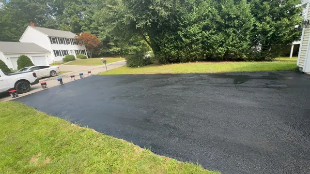 Freshly sealed driveway beside a green lawn