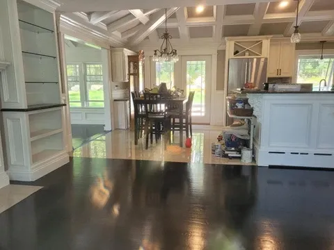 Open concept room with dark floors, dining, and bright kitchen.
