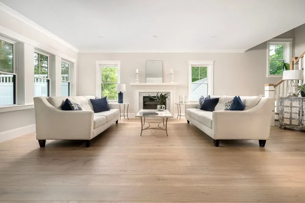 Light-filled living room with two cream sofas, a fireplace, and hardwood floors.