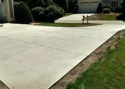 A concrete driveway leading to a house with a fire hydrant in the middle of it.