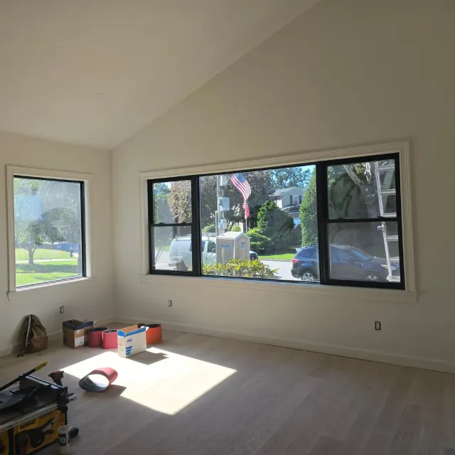 Freshly painted bright living room with white trim, picture windows and prep light wood by Link Services Pro in Auburn, MA