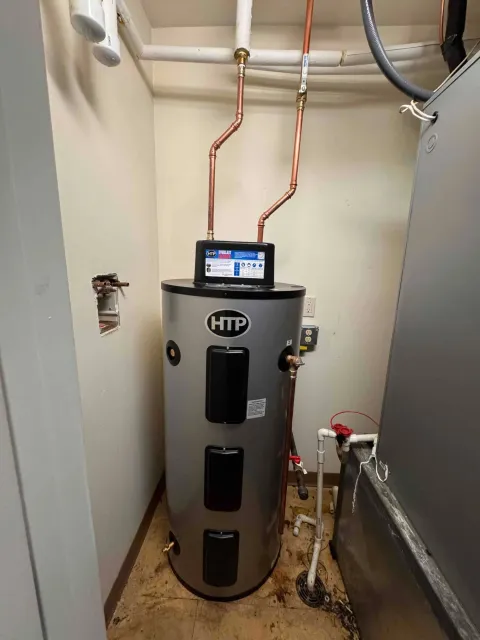 Rheem water heater in a utility closet with copper pipes and a wall-mounted control display