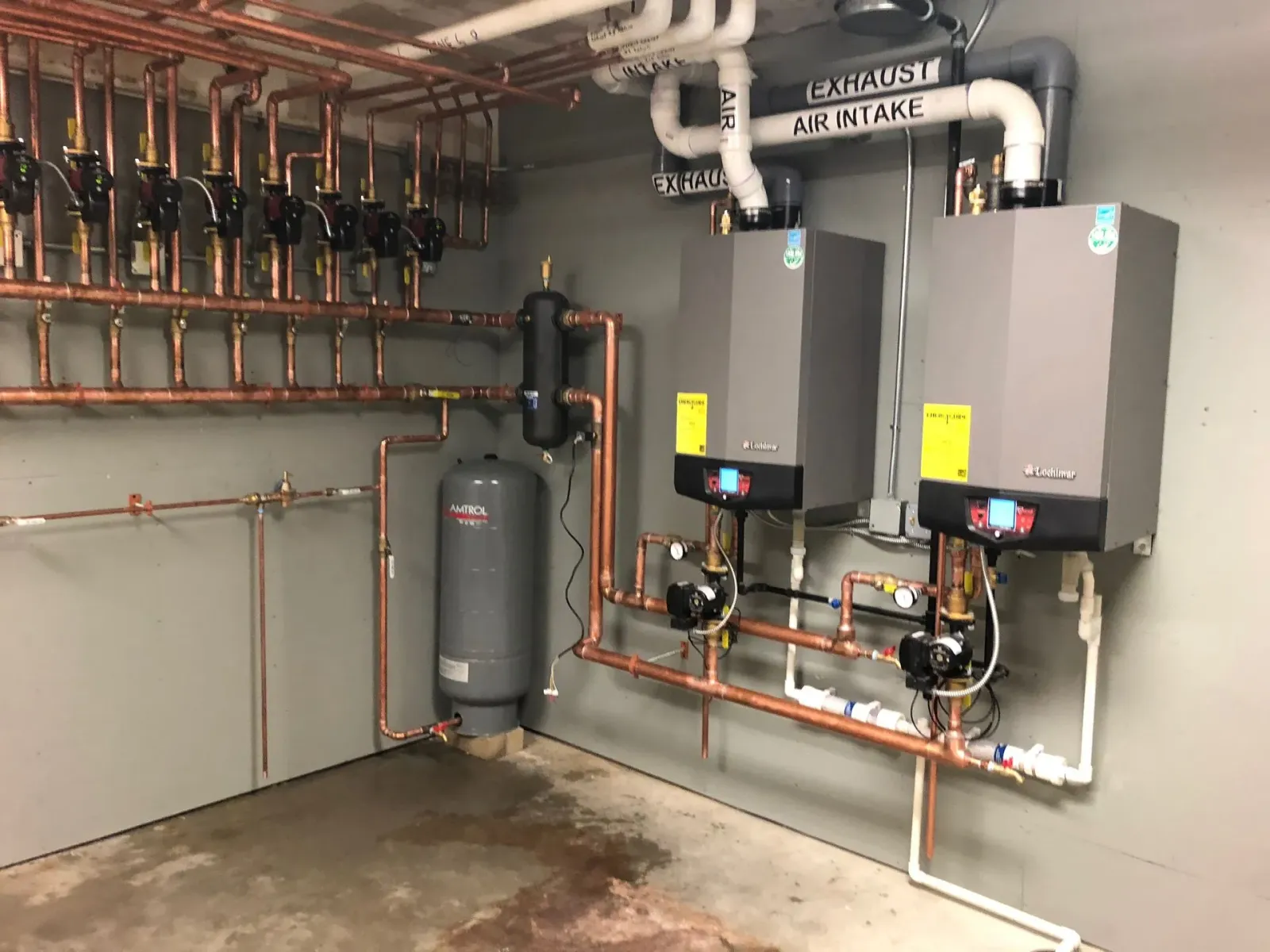 A room with a lot of pipes and boilers on the wall.