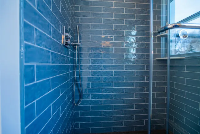 Blue subway-tiled walk-in shower with glass enclosure