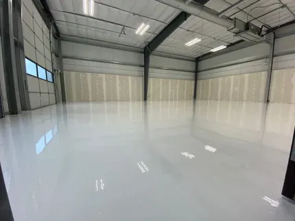 Empty industrial warehouse with glossy white floor and large beige wall panels