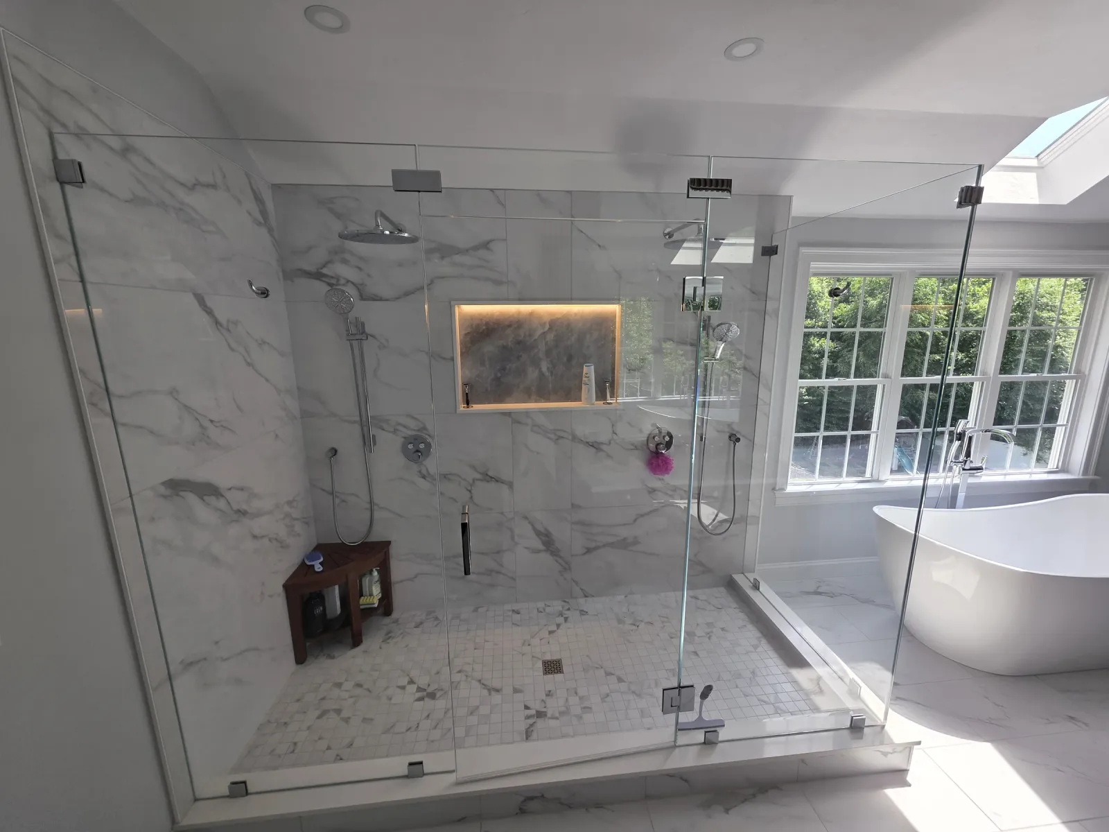 Completed custom shower after tile renovation with glass enclosure, bench, and niche