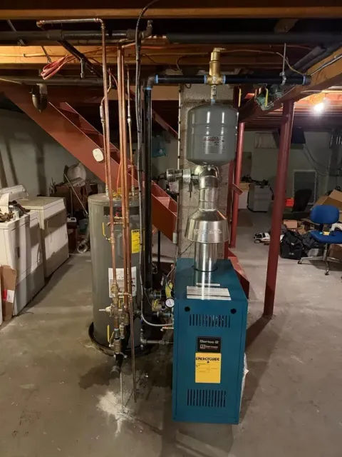 Basement with boiler, hot water tank, expansion tank, copper pipes, and exposed ductwork.
